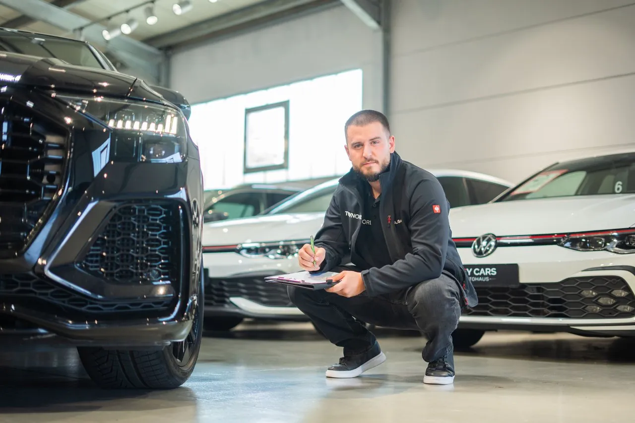 Mitarbeiter des AVG Ingenieurbüros kniet neben einem Fahrzeug in der Halle